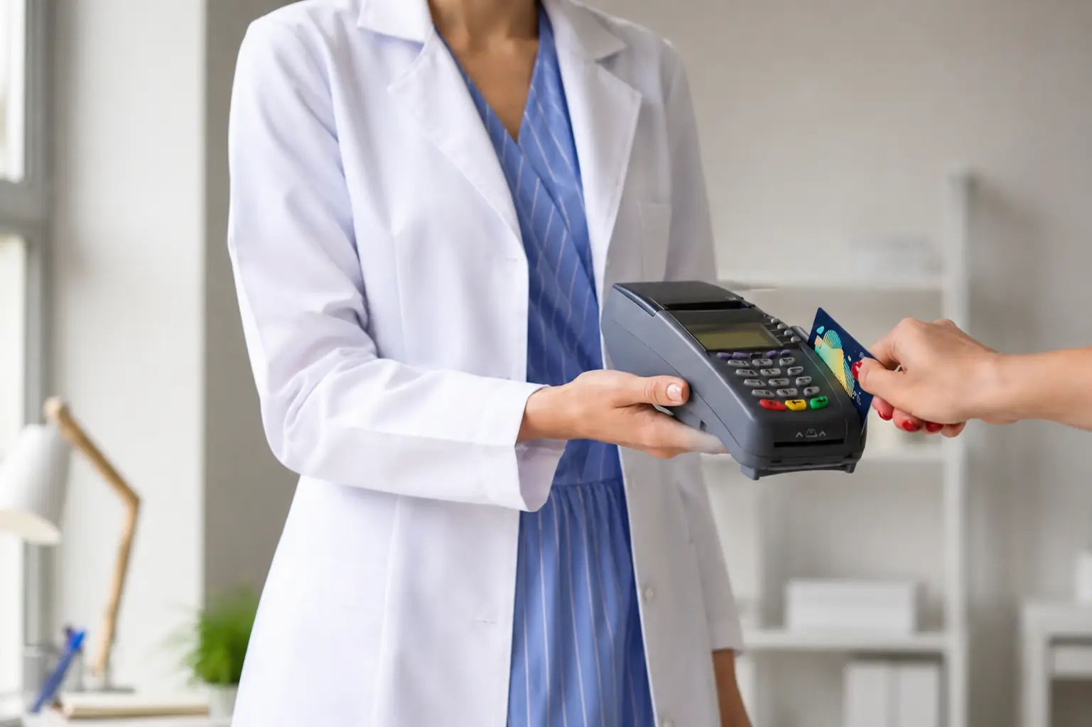 Clinician holding a payment terminal while a patient inserts a credit card